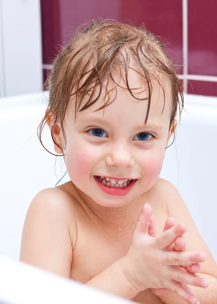 Cute two-year-old girl looking out of a bath and smiling Royalty Free Stock Images