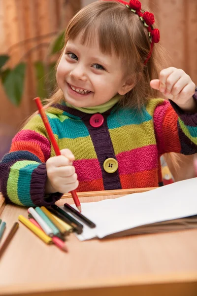 Маленькая девочка рисует карандашами дома — стоковое фото