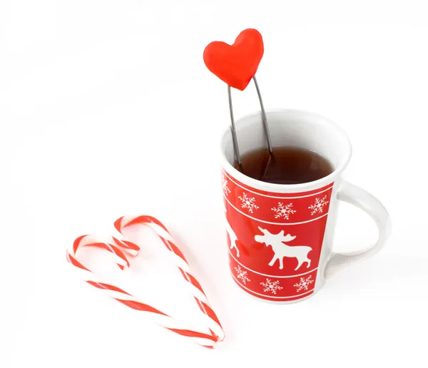 Tea in christmas cup and heart made from striped candy — Stock Photo, Image