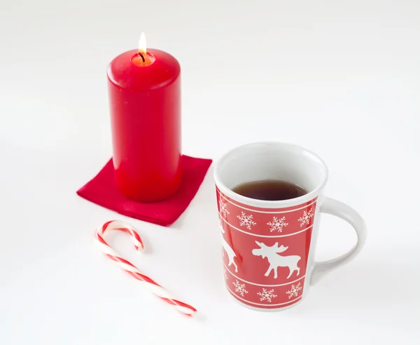 Tea in christmas cup, striped candy and red candle — Stock Photo, Image