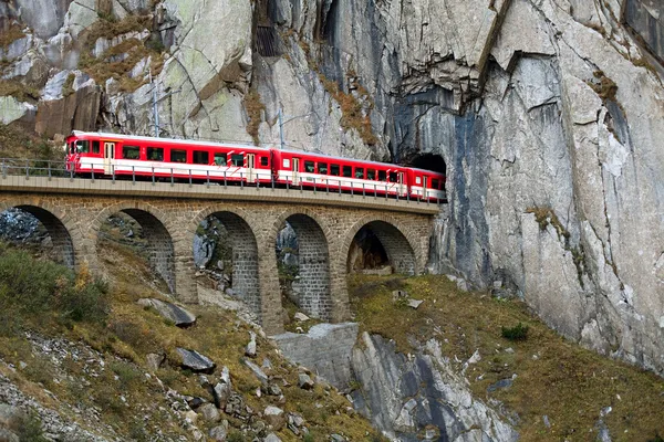 Zug auf alter Brücke fährt in einen Tunnel in den Bergen Stockbild