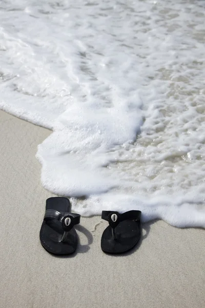 Black flip flops on the beach — Stock Photo, Image