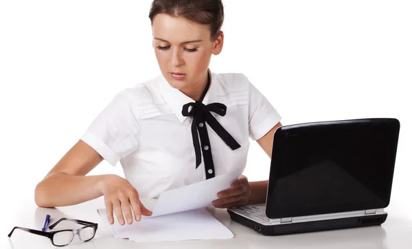 Mujer joven sentada detrás de un escritorio y una computadora revisa los documentos —  Fotos de Stock