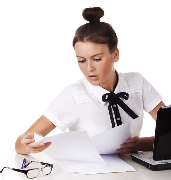 Junge Frau sitzt hinter einem Schreibtisch und ein Computer blättert in den Dokumenten — Stockfoto