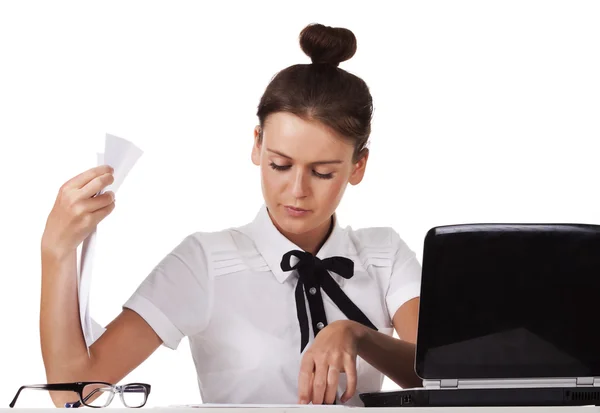 Mujer joven sentada detrás de un escritorio y una computadora revisa los documentos —  Fotos de Stock