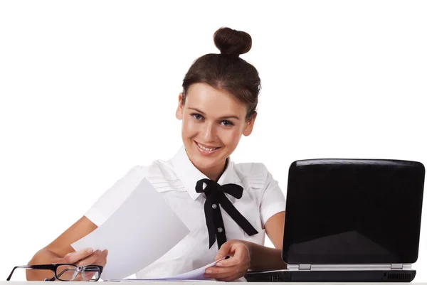 Mujer joven sentada detrás de un escritorio y una computadora revisa los documentos — Foto de Stock