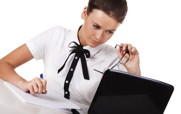 Женщина в очках сидит за столом и работает с ноутбуком Лицензионные Стоковые Изображения