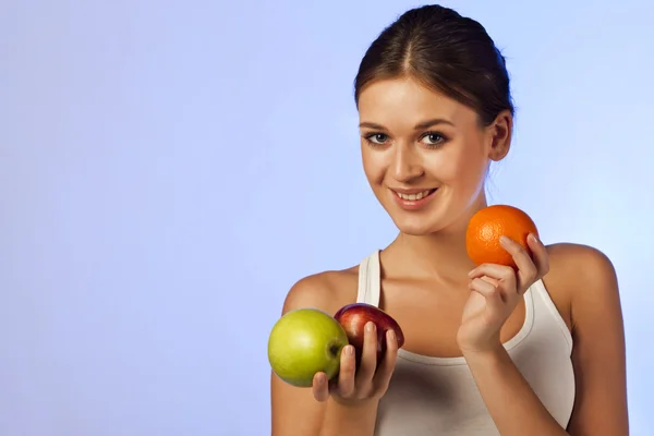 Hermosa morena sosteniendo una fruta manzanas naranjas —  Fotos de Stock