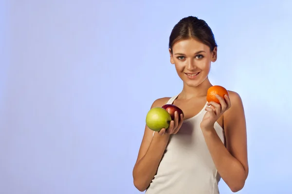 Linda morena segurando uma fruta maçãs laranjas — Fotografia de Stock