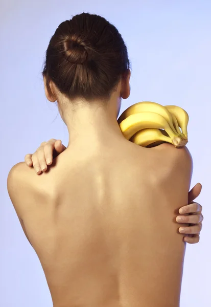 Mujer de pie con su espalda y mantiene los plátanos —  Fotos de Stock