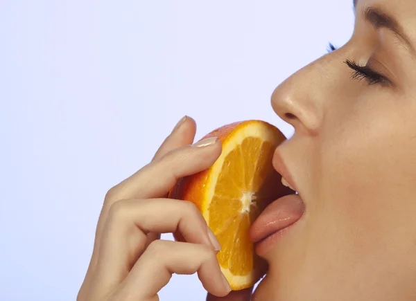 Ung kvinna njuter av en bit av orange — Stockfoto