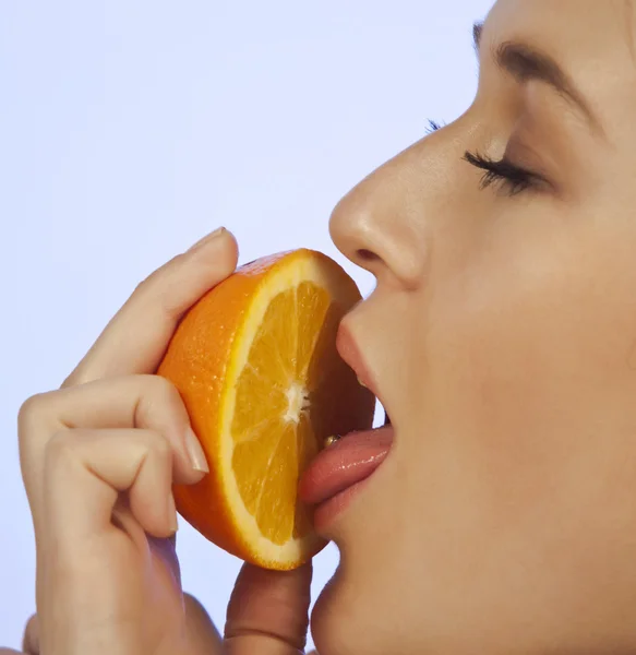 Ung kvinna njuter av en bit av orange — Stockfoto