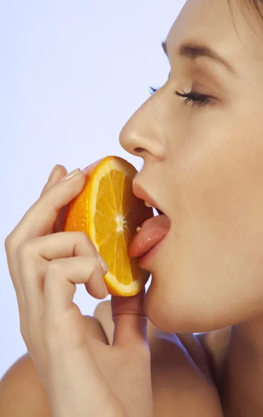 Mujer joven disfrutando de una rebanada de naranja —  Fotos de Stock