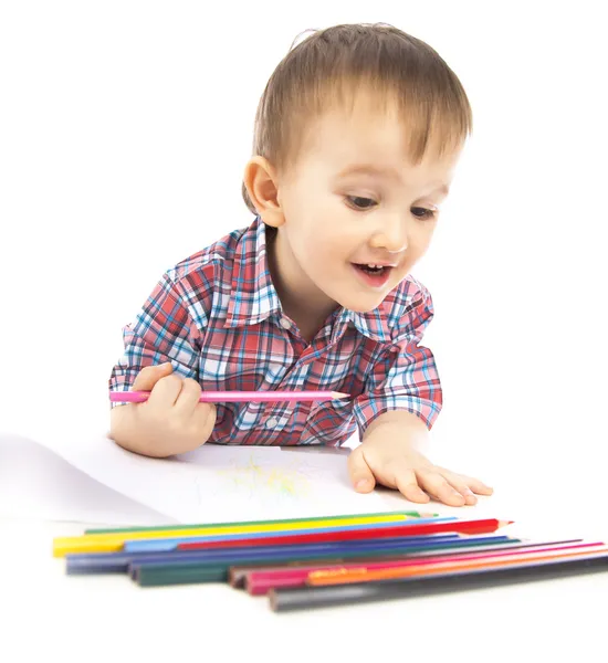 Маленький мальчик за столом рисует цветными карандашами — стоковое фото