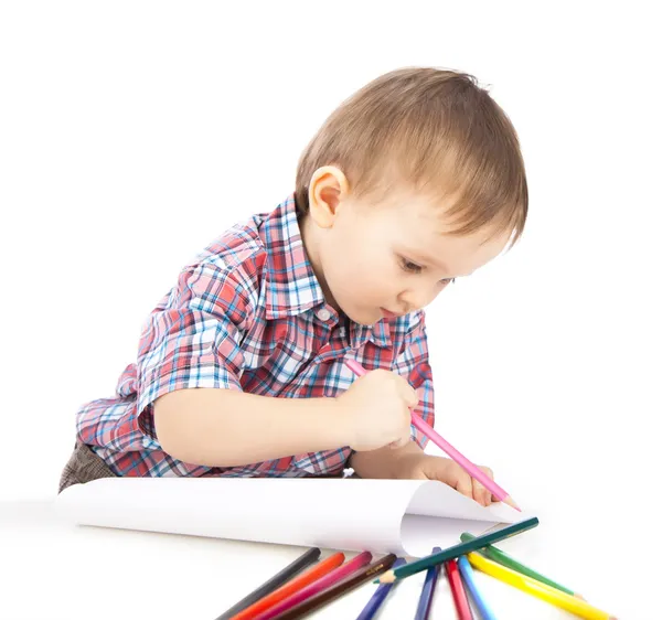 Un niño pequeño en la mesa dibuja con lápices de colores —  Fotos de Stock
