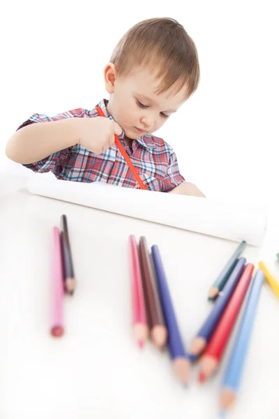 Un bambino a tavola disegna con matite colorate — Foto Stock