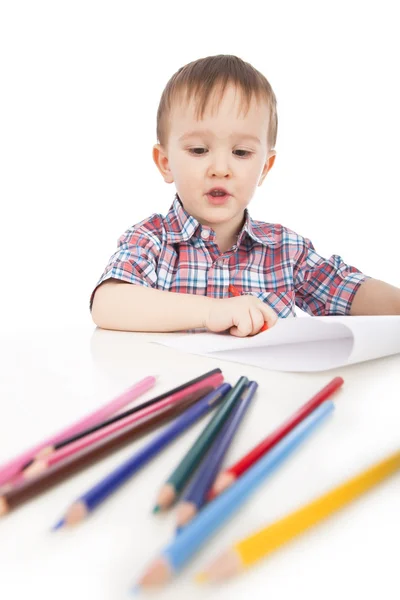 Un niño pequeño en la mesa dibuja con lápices de colores — Foto de Stock