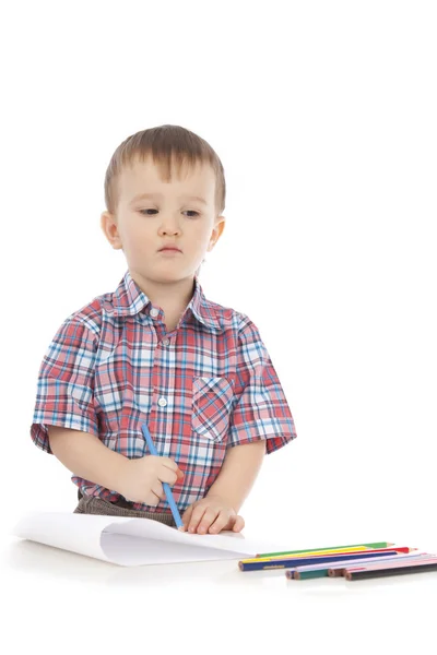 Un niño pequeño en la mesa dibuja con lápices de colores Fotos de stock