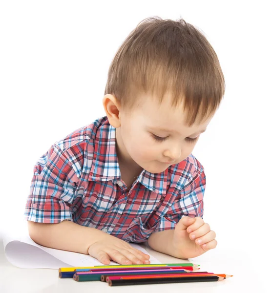 Un petit garçon à la table dessine avec des crayons de couleur Images De Stock Libres De Droits