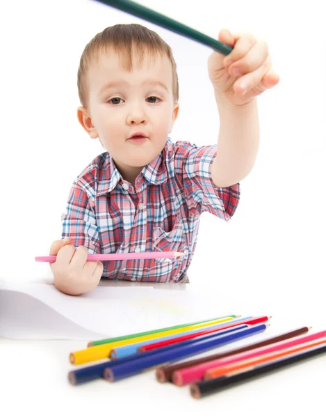 Un niño pequeño en la mesa dibuja con lápices de colores Imágenes de stock libres de derechos