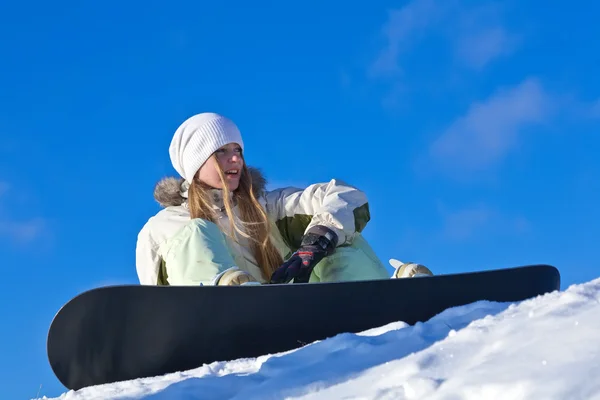 stock image Young woman with snowboard sitting on a slope