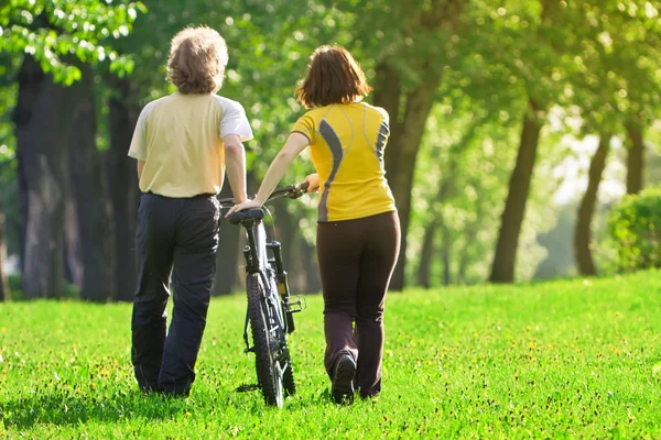 stock image Young couple in the park with a bycicle