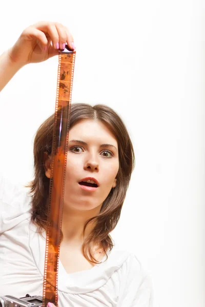 Surprised young woman looking at photofilm tape — Stock Photo, Image