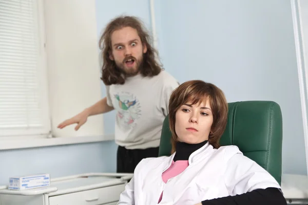 stock image Woman medic and funky patient behind her in the office