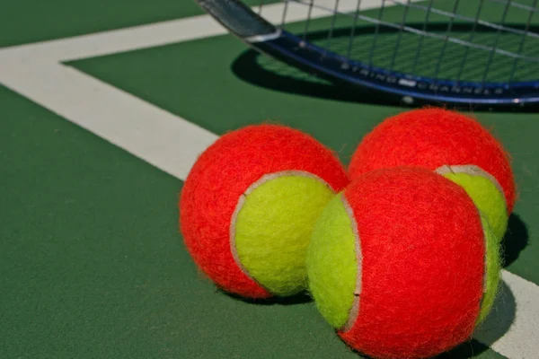 Три теннисных мяча и ракетка — стоковое фото