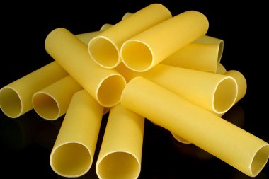Cannelloni pasta tubes on a black background clipart