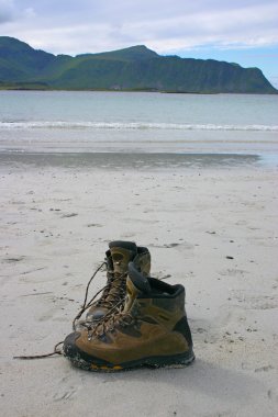 Pair of mountain shoes on the beach clipart