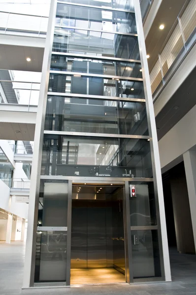 Großer Aufzug aus Glas und Stahl in einem Geschäftshaus Stockbild