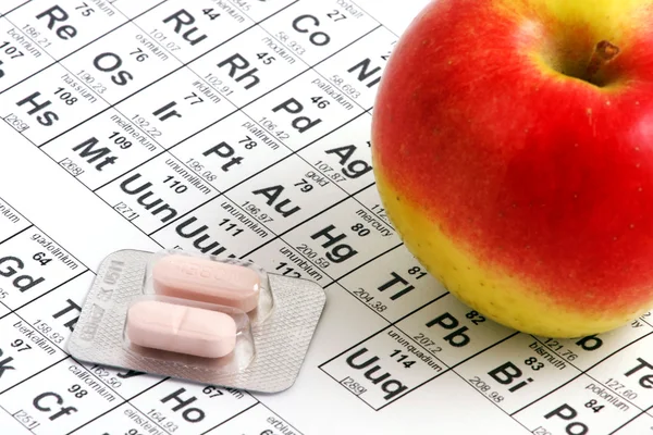 Apple lying on periodic table — Stock Photo, Image