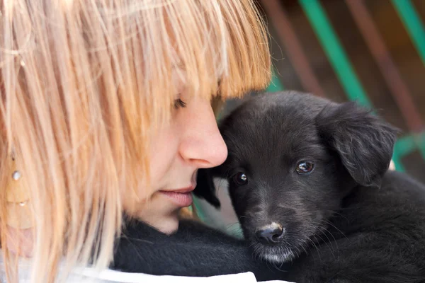 Chica con cachorro negro al aire libre — Foto de Stock
