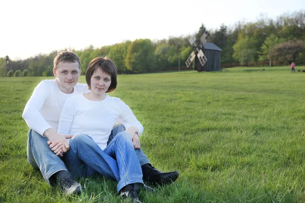 若いカップルは田舎で草の上に座って — ストック写真