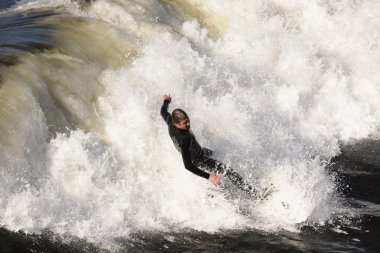 Surfer gets up on a wave. The wave twists with foam and splashes. clipart