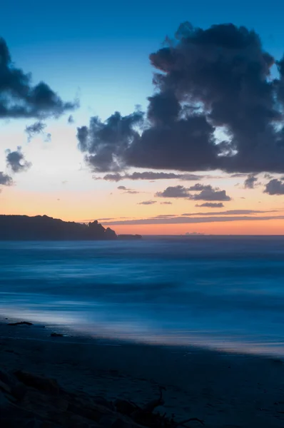 Una Playa Atardecer Con Cielo Resplandeciente Nubes Oscuras — Foto de Stock