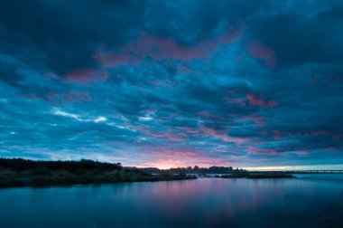 Günbatımı ile bulutlar yanan bir nehir üzerinde