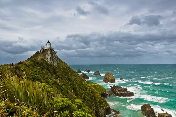 stock image Nugget Point Light House and dark clouds in the sky