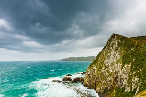 Cliffs under thunder clouds and turquoise ocean — Stock Photo, Image
