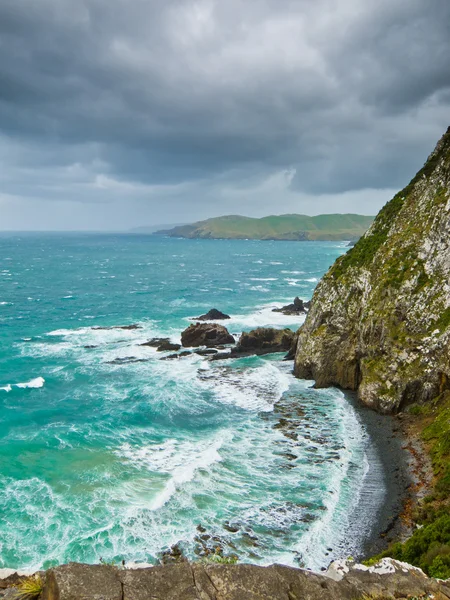 Cliffs under thunder clouds and turquoise ocean — Stock Photo, Image