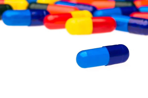 Een blauwe capsule tegenover veel kleurrijke — Stockfoto
