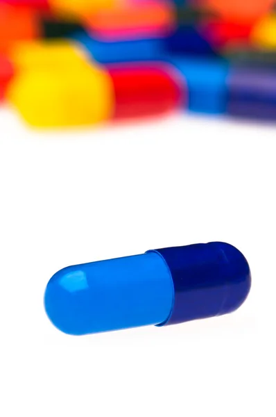 Una cápsula azul delante de muchos coloridos — Foto de Stock