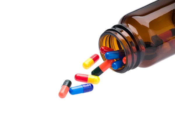 Flacone farmaceutico aperto che versa capsule colorate — Foto Stock