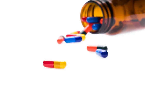 Flacon pharmaceutique ouvert qui renverse des capsules colorées — Photo