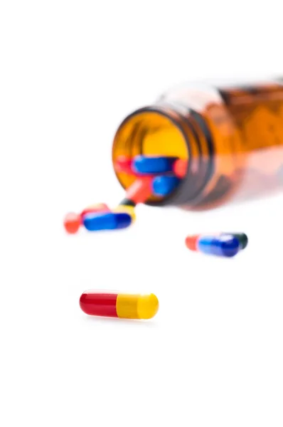 Flacone farmaceutico aperto che versa capsule colorate — Foto Stock