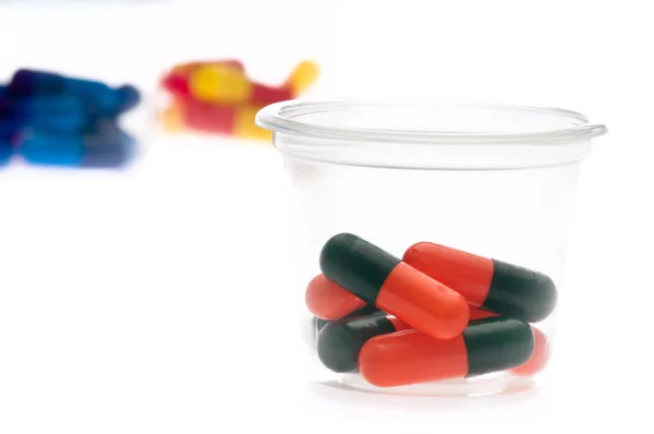 Bunte Tabletten, Kapseln in einer Tasse — Stockfoto