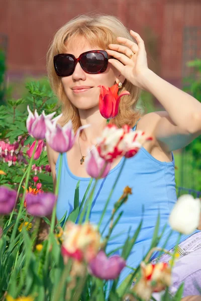 Woman in flowers with sunglass — Stock Photo, Image
