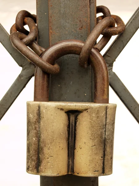 stock image The old padlock and rusty chain on a metal lattice.