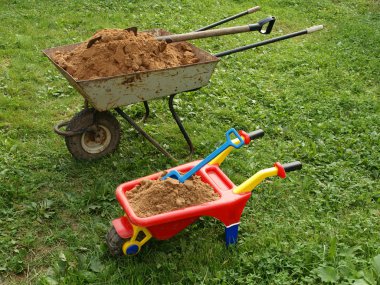 Two wheelbarrows with sand on green to a grass. clipart